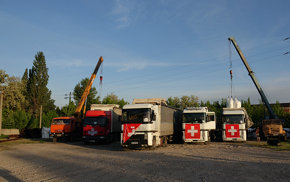 Kräne verladen Hilfsgüter auf die Lastwagen des Hilfstransports.