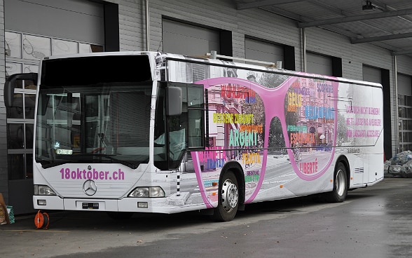 Ein bunt bemalter Bus steht vor einer Halle.