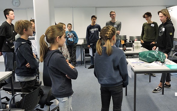 Groupe de jeunes écoutant les explications d’un collaborateur du DFAE. 