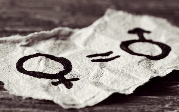 A female symbol, an equals sign and a male symbol drawn on a piece of paper.