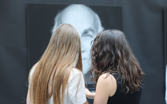 Deux jeunes élèves regardent une affiche dans une exposition.