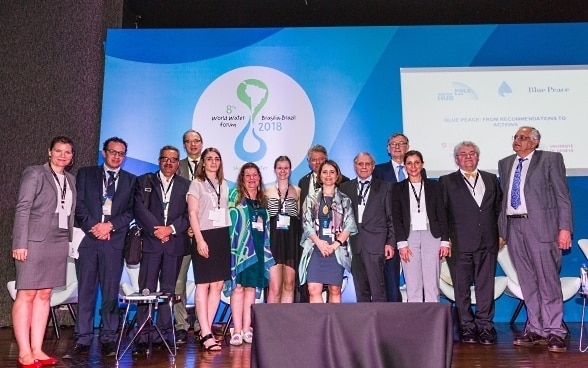 Six femmes et neuf hommes de nationalités différentes devant un mur bleu avec le logo du Forum mondial de l'eau à Brasilia.