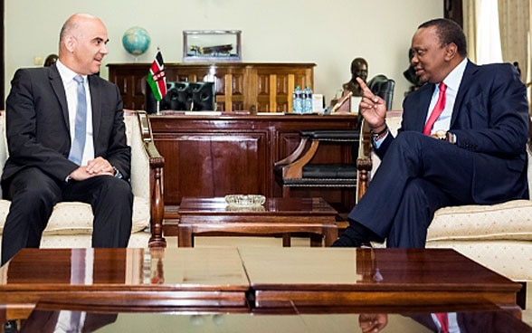 Bundespräsident Berset und der kenianische Präsident Kenyatta sitzen an einem Holztisch und diskutieren.