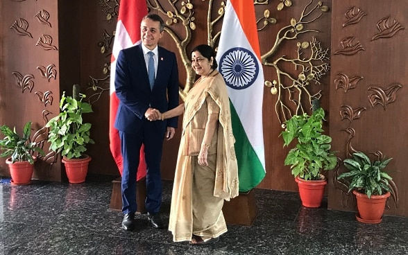 Federal Councillor Cassis shakes hands with Indian Foreign Minister Sushma Swaraj. In the background are the flags of India and Switzerland.