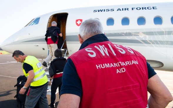 Experts from the Swiss Humanitarian Aid Unit (SHA) board an aircraft belonging to the Swiss Confederation in Belp.