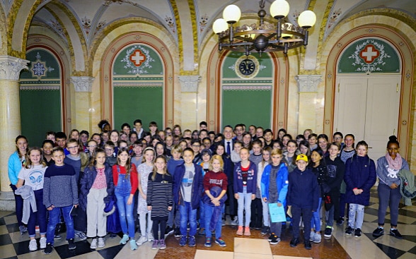 Around 80 children pose for a group photo. In the middle is Federal Councillor Ignazio Cassis.