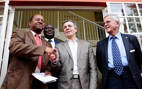 Le conseiller fédéral Ignazio Cassis serre la main du ministre de la santé du Zimbabwe, Obadiah Moyo, tandis que le professeur Ruedi Luthy, fondateur d'une clinique financée par la Suisse, assiste à sa visite.