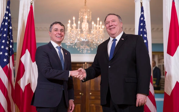 Federal Councillor Ignazio Cassis shakes hands with US Secretary of State Mike Pompeo in Washington. The flags of Switzerland and the USA can be seen in the background.