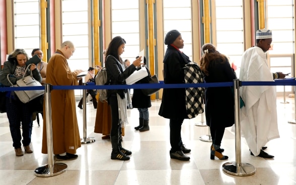 Des femmes et des hommes attendent l'inscription dans une grande salle.