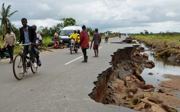 Des locaux essaient de rouler sur les restes de la route principale, après le cyclone Idai.