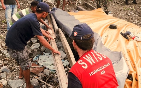 Un membre du Corps suisse d'aide humanitaire aide la population locale à reconstruire les infrastructures sanitaires après une catastrophe.