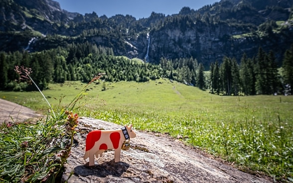 A red spotted cow made of wood stands in a Swiss mountain landscape.