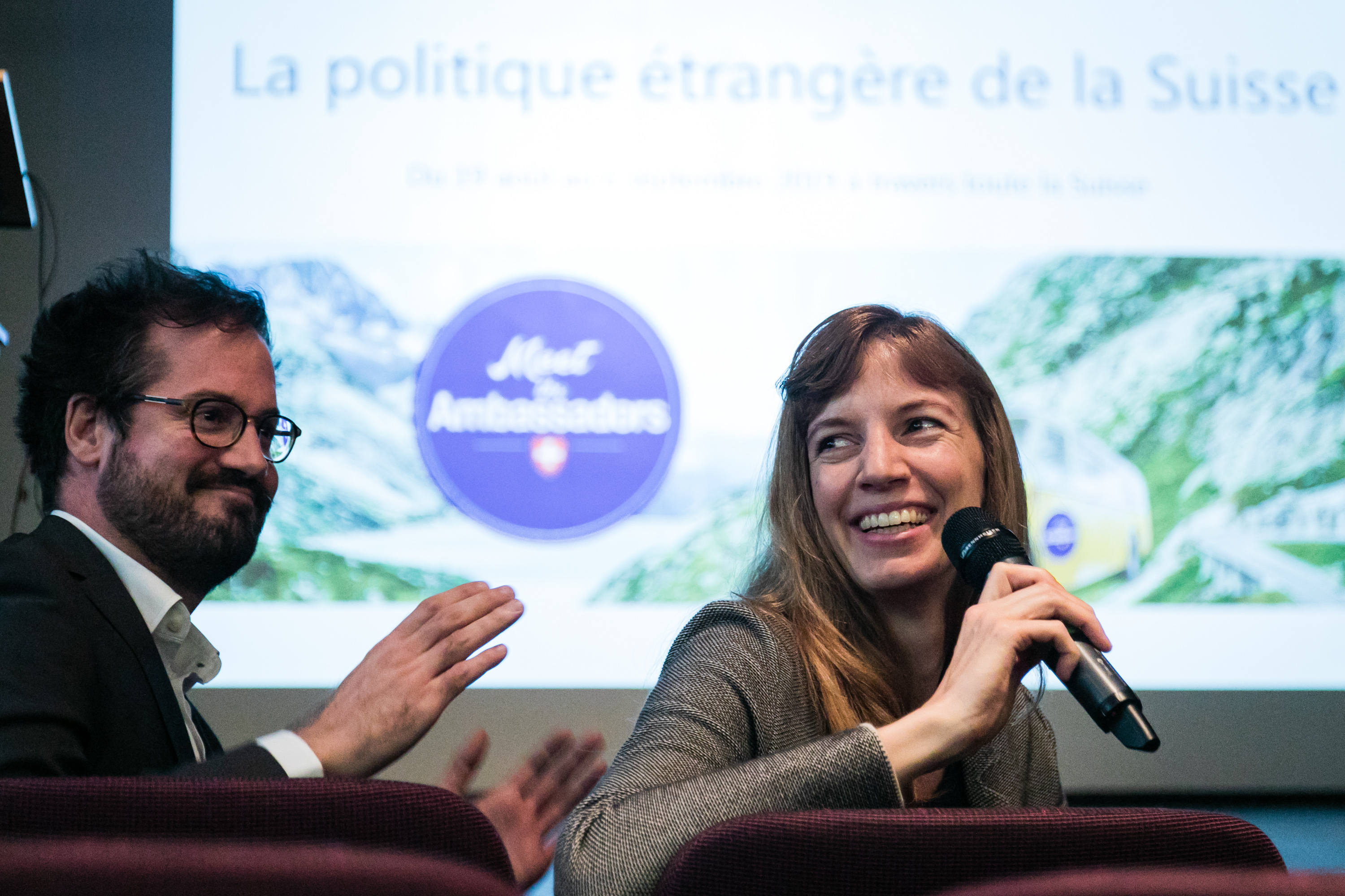 A diplomat sits in the front row and answers the audience with the microphone in her hand