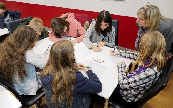 Children write on a sheet of paper.