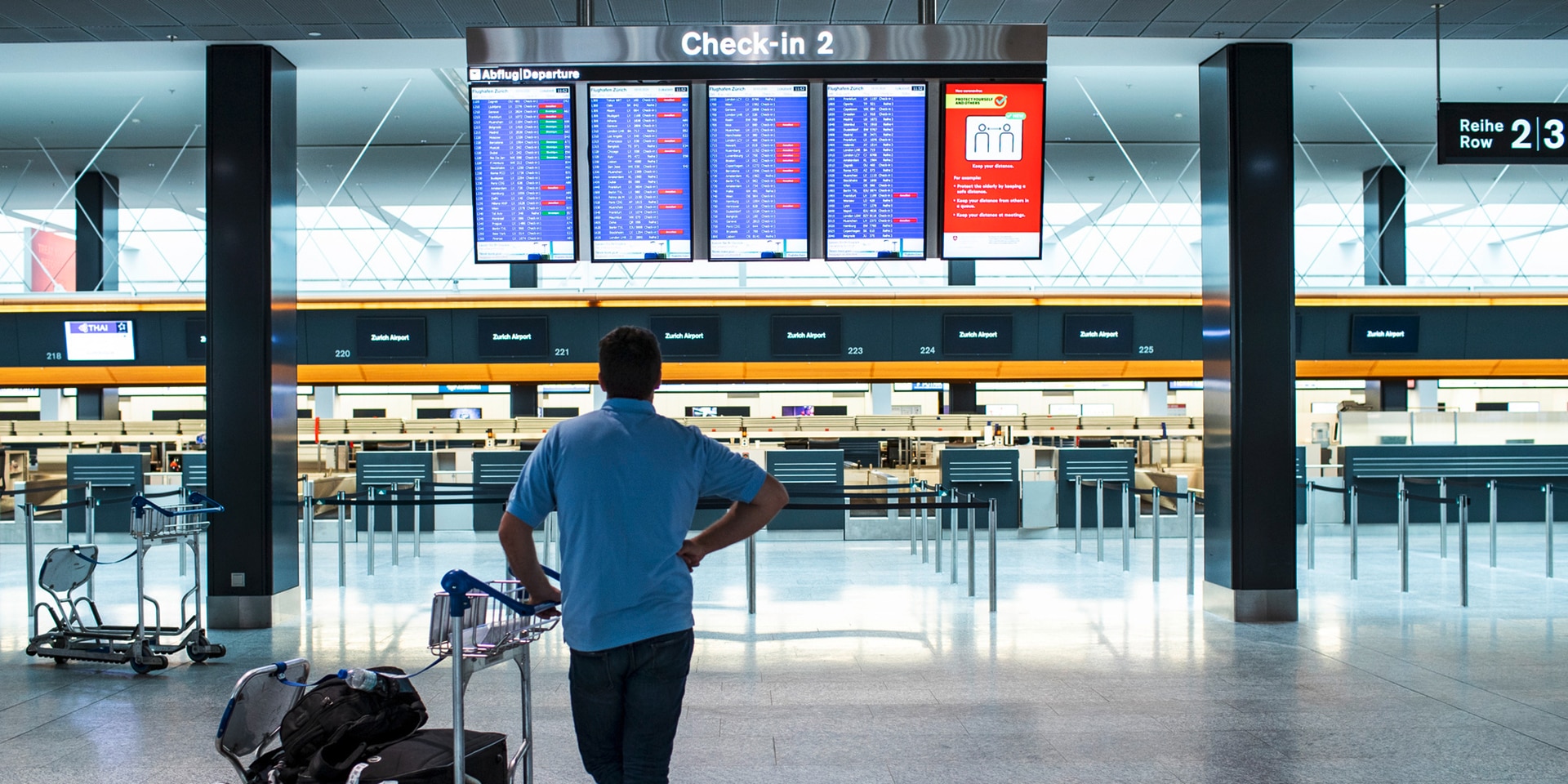 Un uomo studia il piano delle partenze in aeroporto.