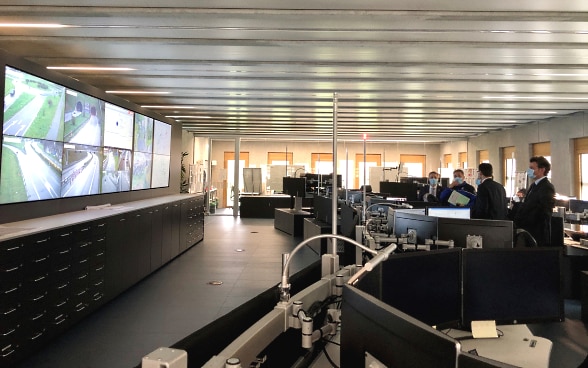 Le conseiller fédéral Cassis est debout dans la salle de contrôle du centre d'urgence cantonal et regarde les écrans sur le mur.