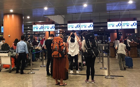  In der Flughalle des Flughafens von Yangon stehen Passagiere in Warteschlangen vor dem Check-In-Schaltern. 