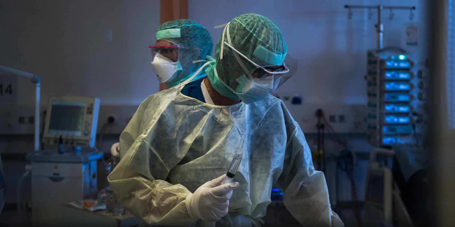  Two people in protective clothing working with medical instruments.