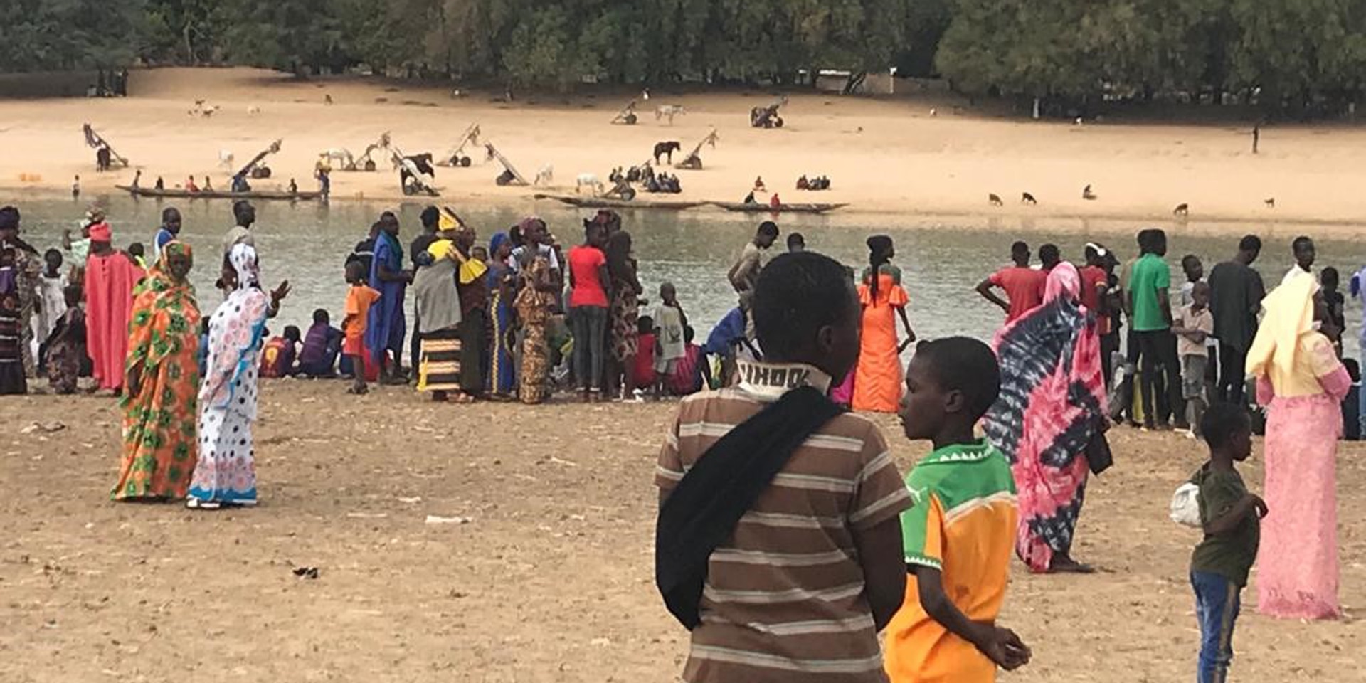 Alcune persone che indossano abiti colorati si riuniscono sulla riva del fiume Senegal, che separa il Senegal dalla Mauritania.