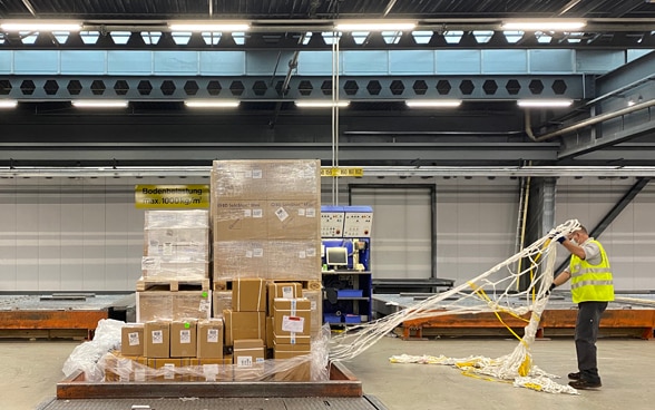 Ein Logistiker in einer Leuchtweste fertigt mehrere Dutzend Kartonkisten mit Hilfsgütern für den Flug nach Venezuela in Zürich ab. 