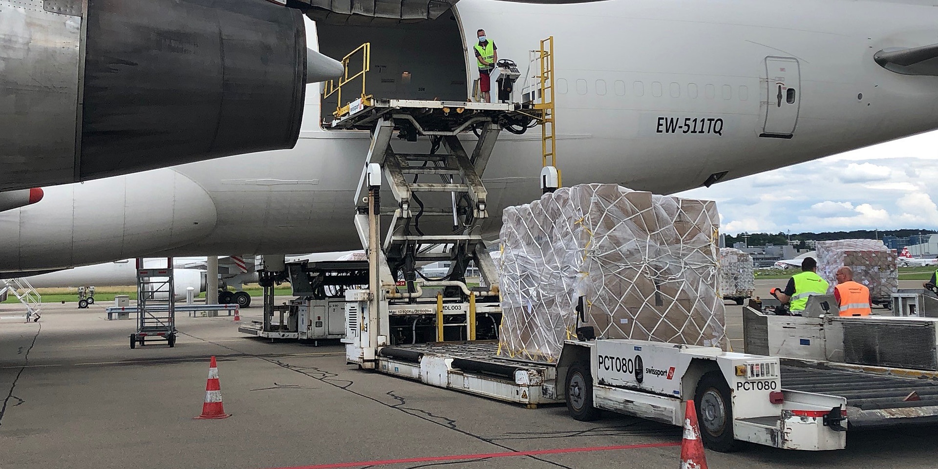  A logistician in a light vest handles several dozen cardboard boxes with relief supplies for the flight to Venezuela. 