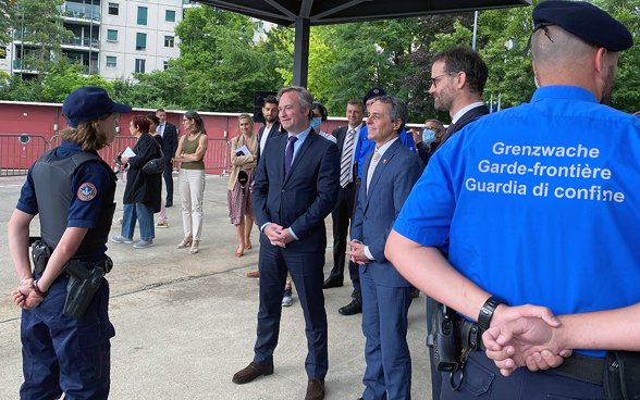 Bundesrat Ignazio Cassis, Staatssekretär Lemoyne und der Genfer Staatsratspräsident António Hodgers sprechen mit französischen und Schweizer Grenzwächtern.