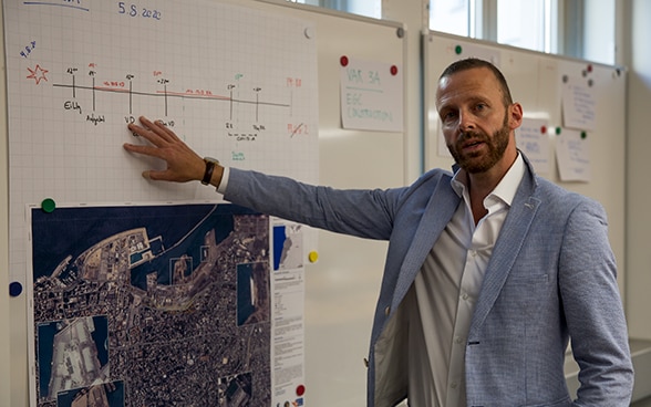 Il capo intervento Silvio Flückiger indica una mappa della città di Beirut appesa alla parete nella sala di crisi dell’Aiuto umanitario svizzero. 