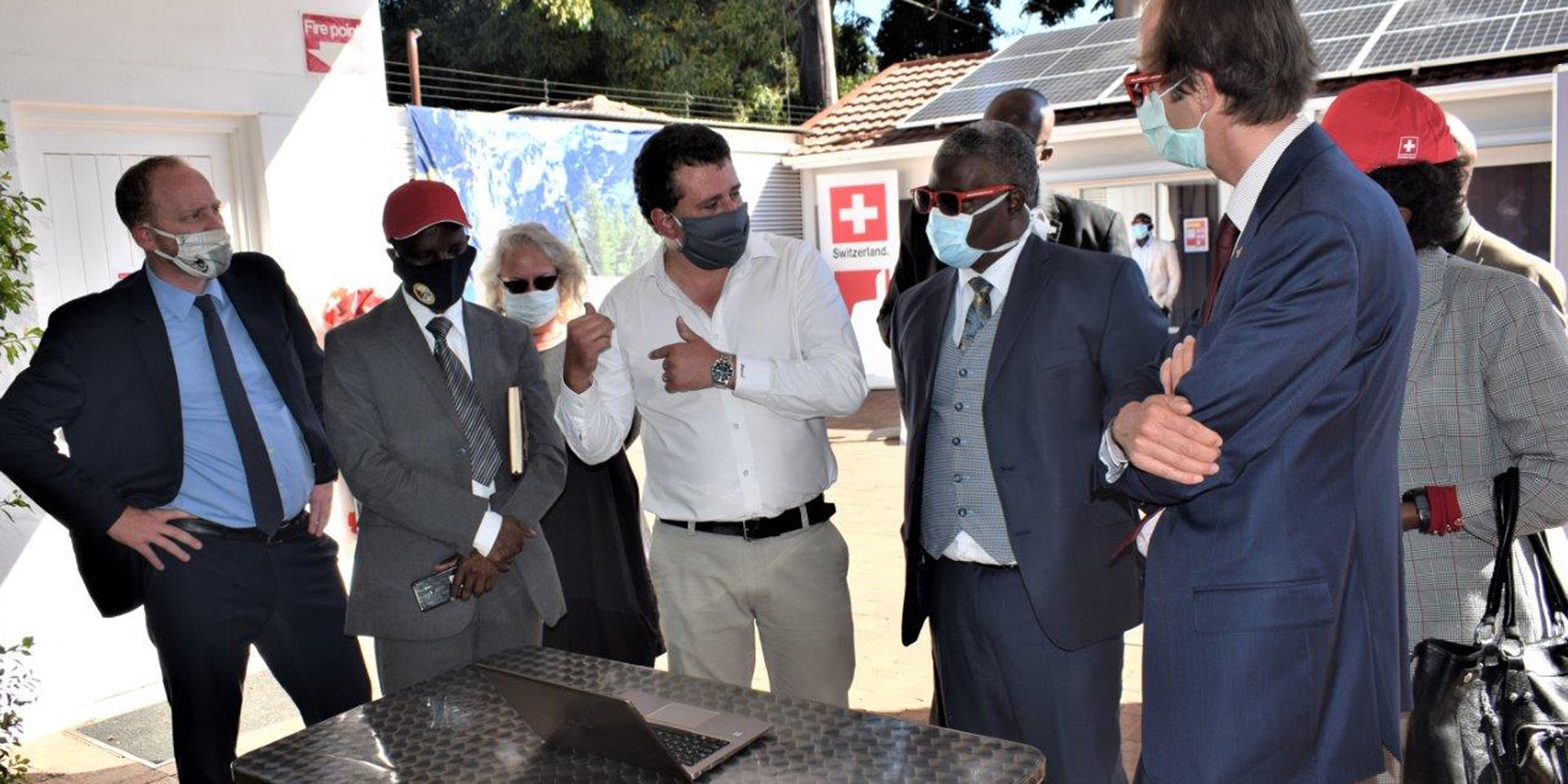 Le ministre Fortune Chasi, l’ambassadeur Niculin Jäger et d’autres personnes discutent debout autour d’une table, à l’Ambassade de Suisse.