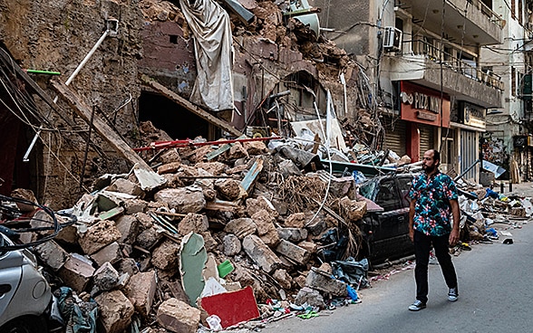 A man walks past a completely destroyed house. 