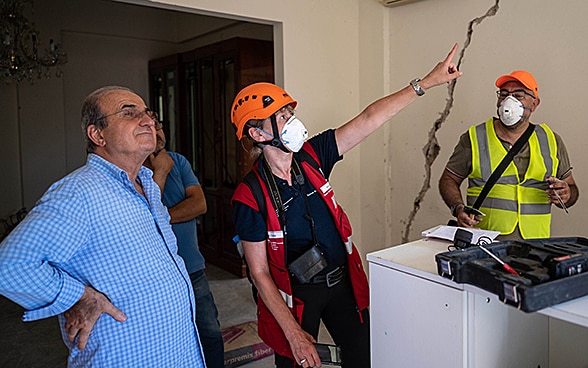 Un expert du Corps suisse d'aide humanitaire discute avec un habitant des dommages causés à sa maison.