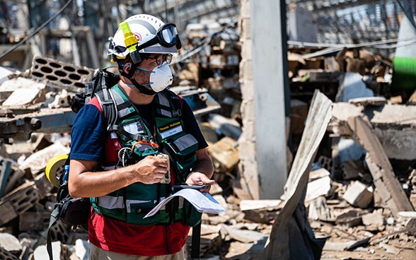 A Swiss Humanitarian Aid expert is standing in the middle of the debris at the port of Beirut.