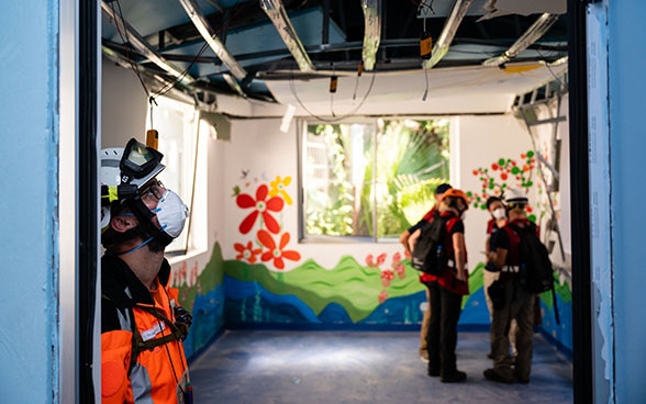 Un expert de l'Aide humanitaire suisse examine le plafond démoli d'un hôpital.
