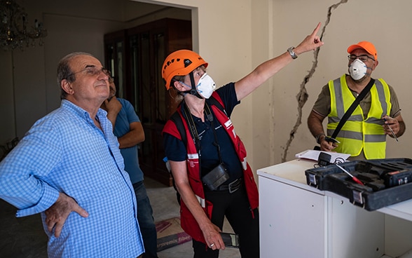 Vista su un appartamento distrutto e senza finestre. L'ingegnere Regina Wenk, sul balcone, si consulta con un membro delle autorità mentre ispeziona l’edificio.  