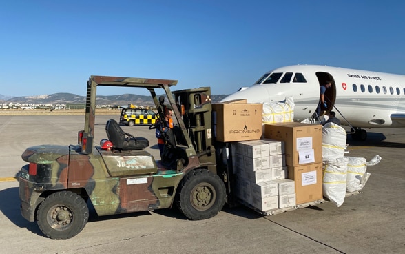 Ein Gabelstapler transportiert Kisten und Säcke mit Hilfsgütern vom Flugzeug weg.