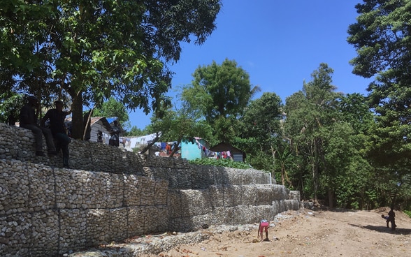 Stone structures are erected on the sides of a dirt road.