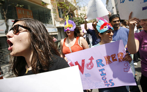 A group of people is demonstrating in the street holding signs saying "Worker's rights".