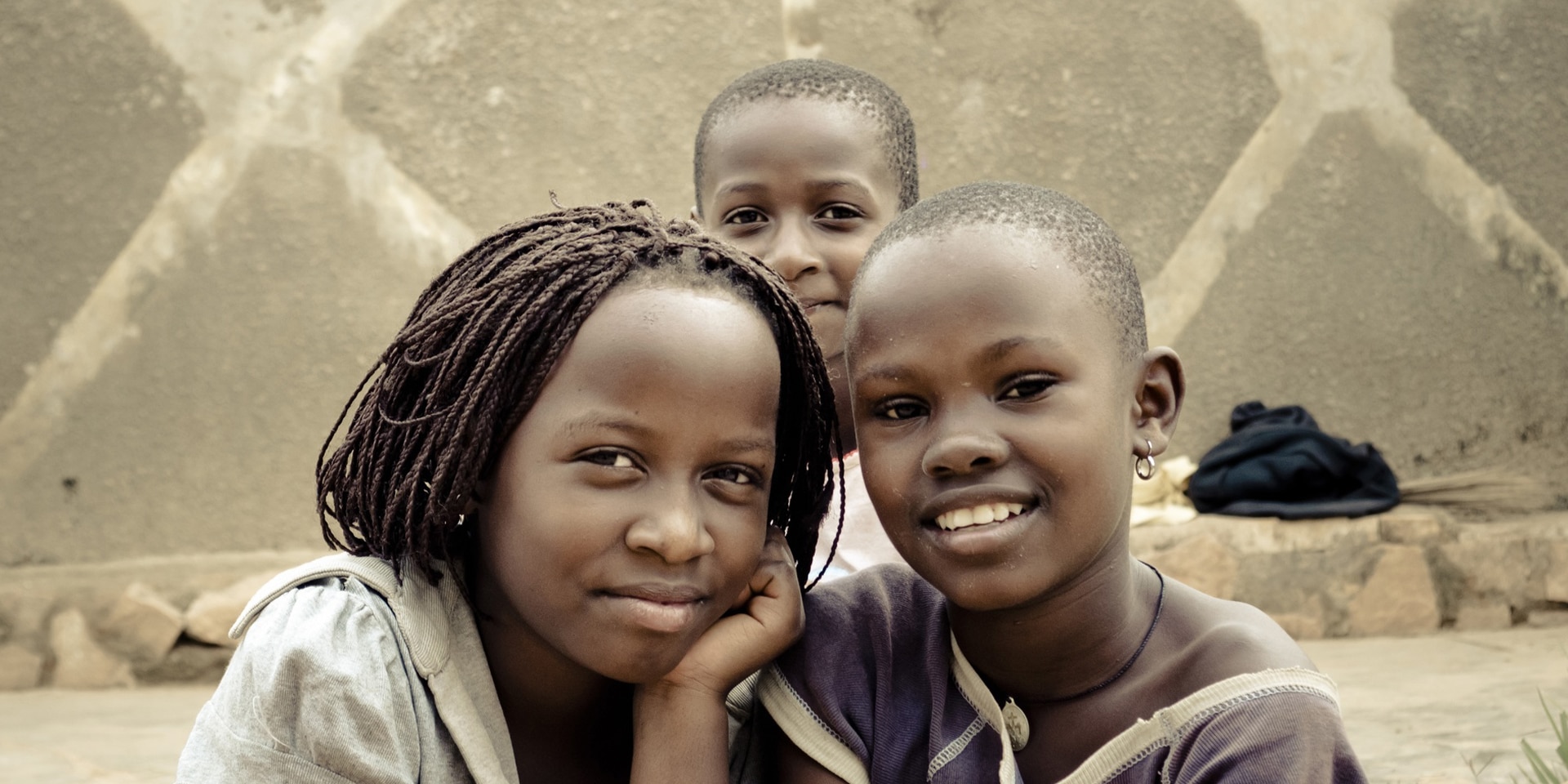 Tre bambini di strada posano davanti all’obiettivo di una macchina fotografica a Kampala, Uganda.