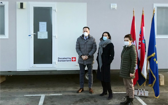 In piedi davanti a un’unità abitativa l’ambasciatrice svizzera Emilija Georgieva, la segretaria di Stato Irena Petrijevčanin Vuksanović (Ministero degli Interni) e il segretario di Stato Zdenko Lucić (Ministero degli Affari Europei ed Esteri).