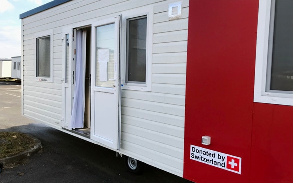 A mobile housing unit with the inscription "donated by Switzerland".
