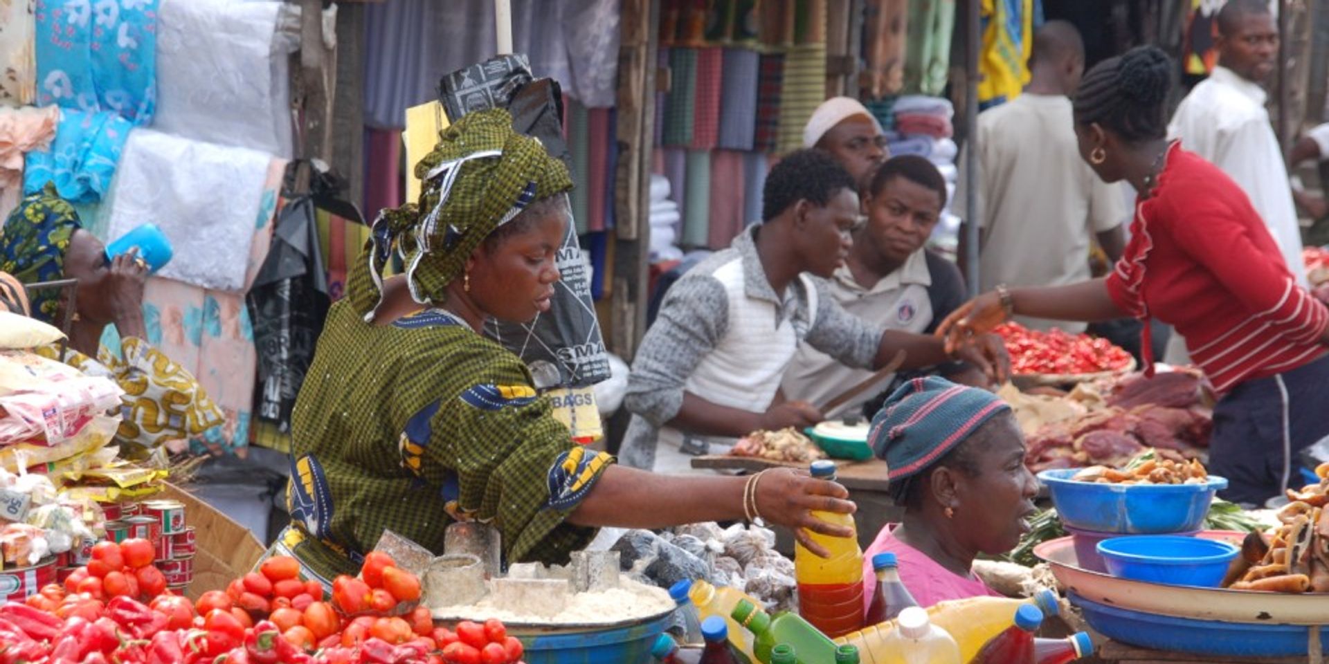 Eine Frau greift auf einem Marktstand in Afrika nach einer Flasche, um sie zu verkaufen.
