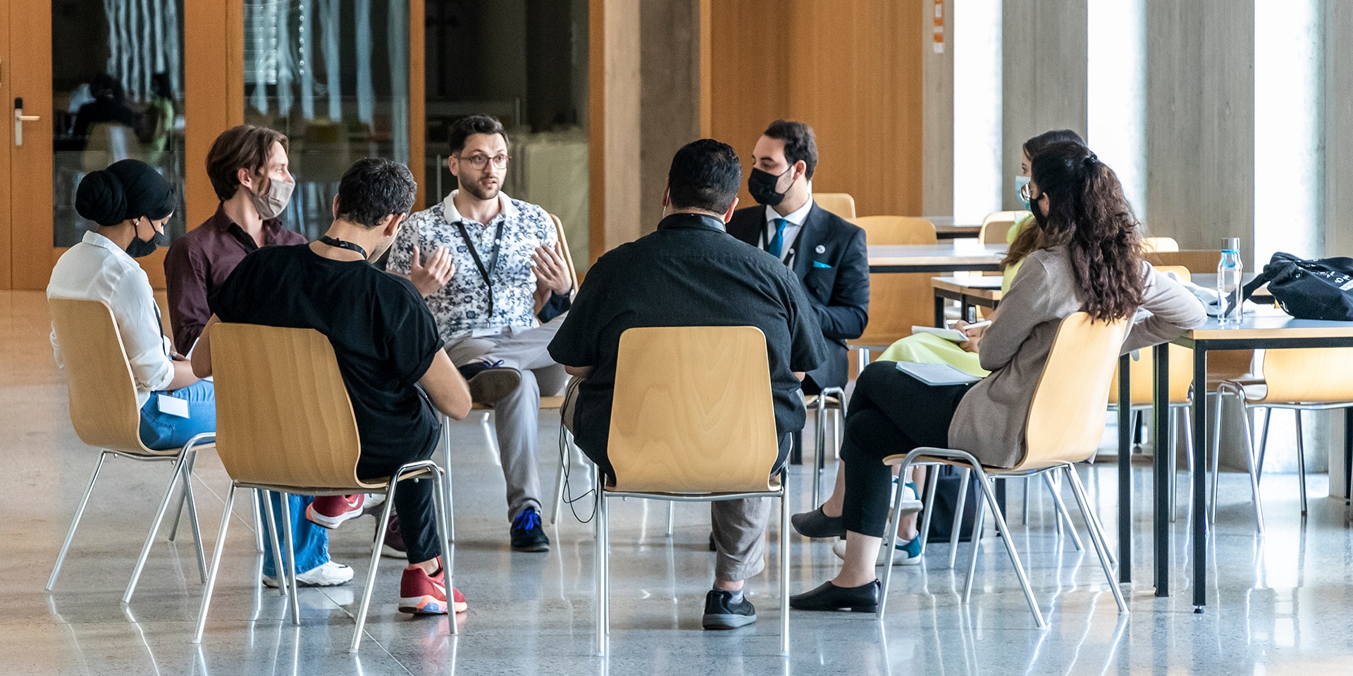 Young participants of the MEM Summer Summit sitting on chairs in a circle and discussing a topic..