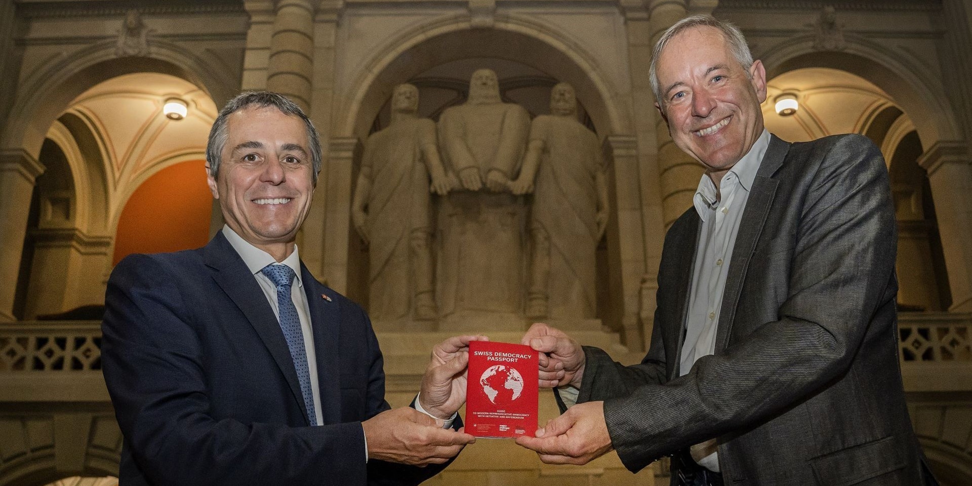 Federal Councillor Ignazio Cassis and Bruno Kaufmann pose with the Swiss Democracy Passport.