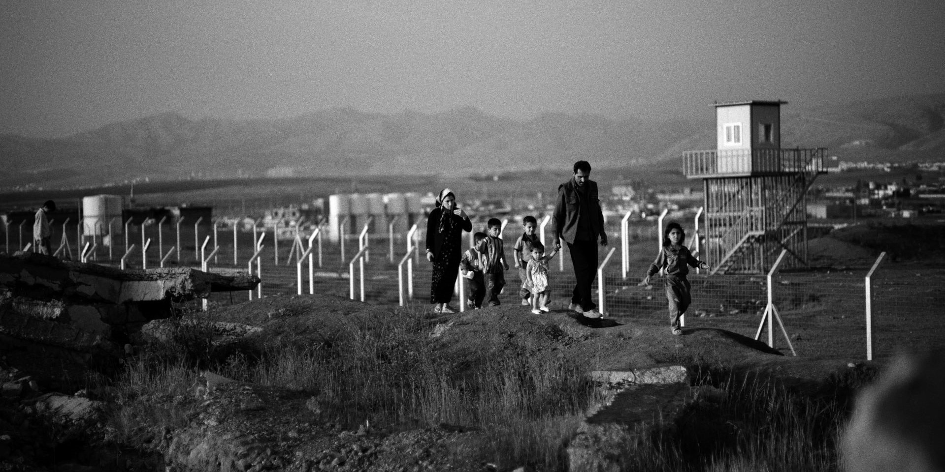 An Iraqi family walks through a field that has been bombed by cluster munitions.