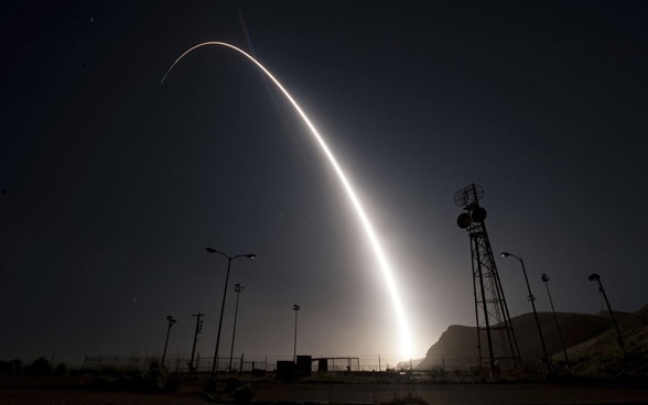 Night sky and a rocket leaving a tracer in its wake. 