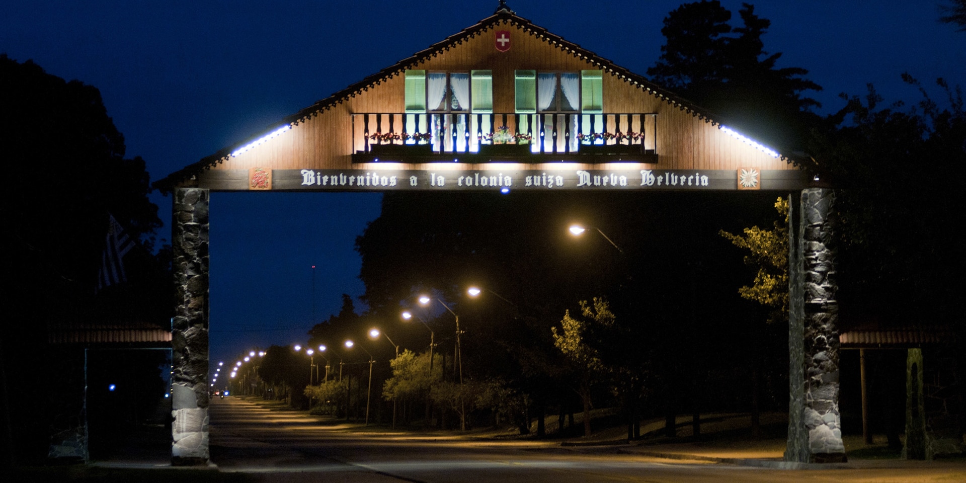 Nächtliche Szenerie einer Strasse und einem Portal, das ein Chalet mit Schweizer Motiven darstellt.