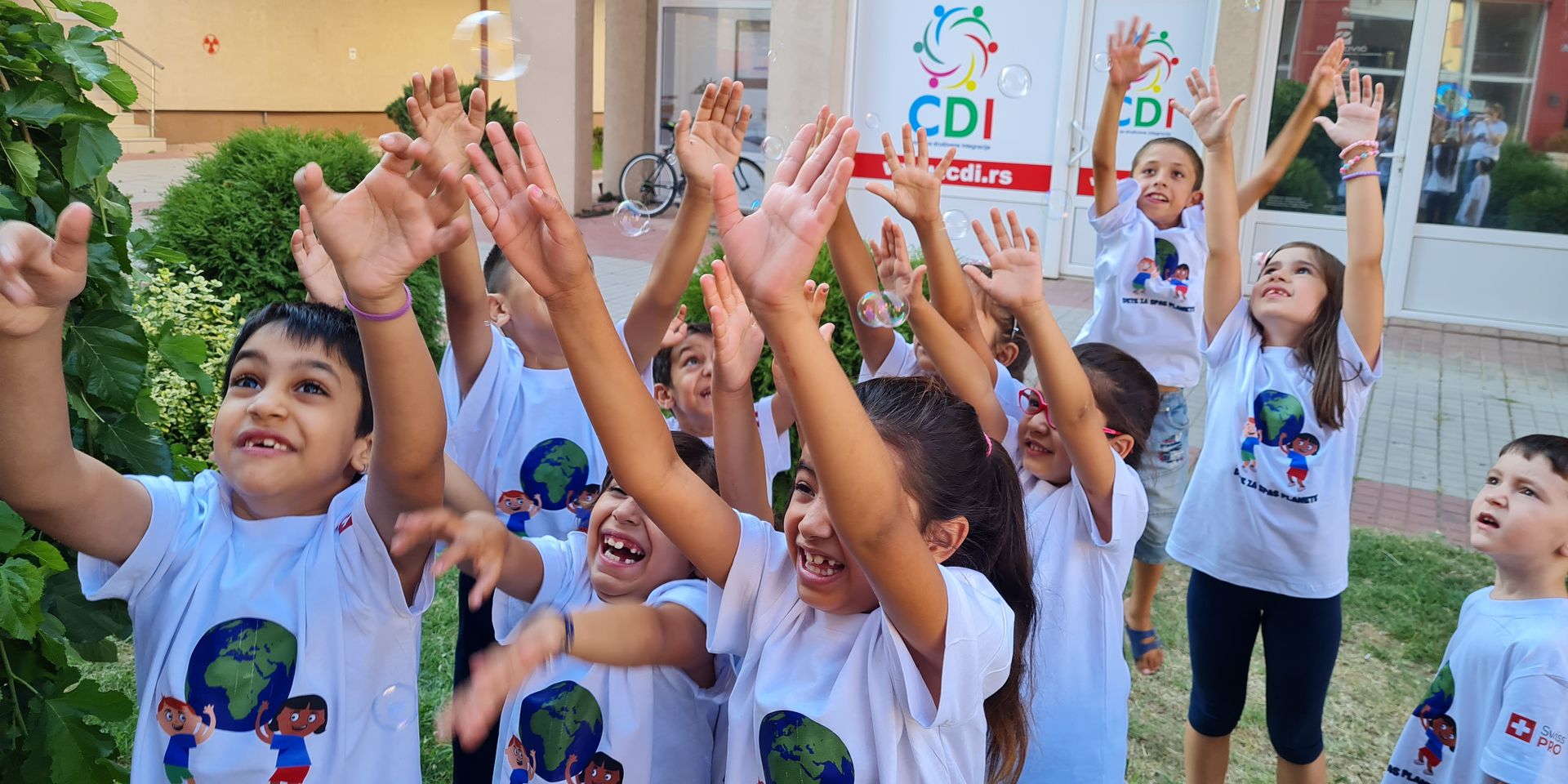 A group of children holding their hands up in the air and laughing.