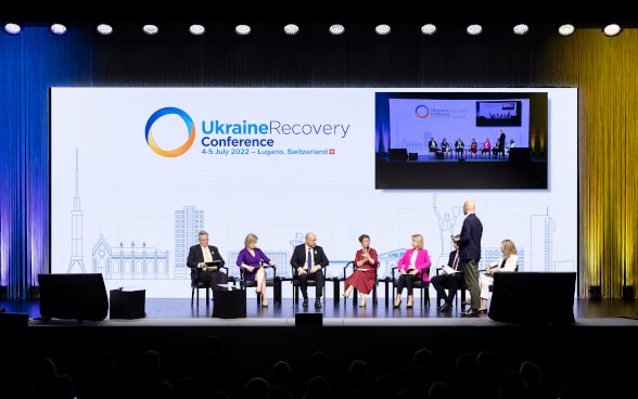 Von links nach rechts: Matthias Cormann (OECD), Elizabeth Truss (UK), Denys Shmyhal (UA), Odile Renaud-Basso (EBRD), Teresa Czerwinska (EIB), Valdis Dombrovskis (Europäische Kommission) und Anna Bjerde (Weltbank) sprechen während der Plenarsitzung der Konferenz.