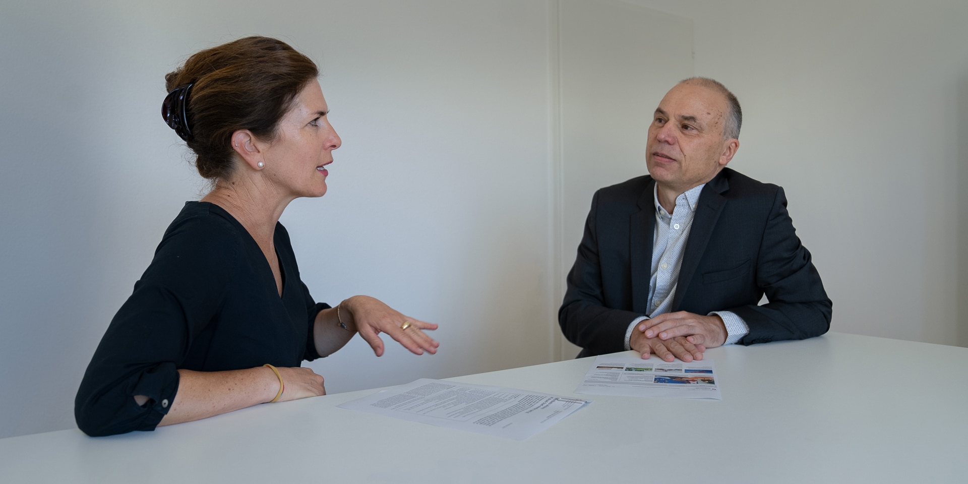 Debora Kern and Daniel Birchmeier seated at the same table, looking at some papers and engaged in animated discussion.