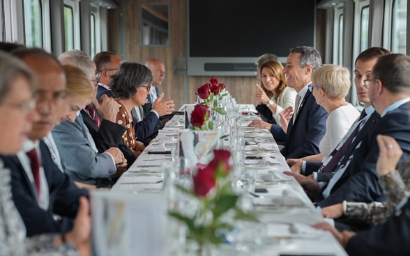 Le président de la Confédération Ignazio Cassis discute avec quelques passagers dans le wagon du train spécial.