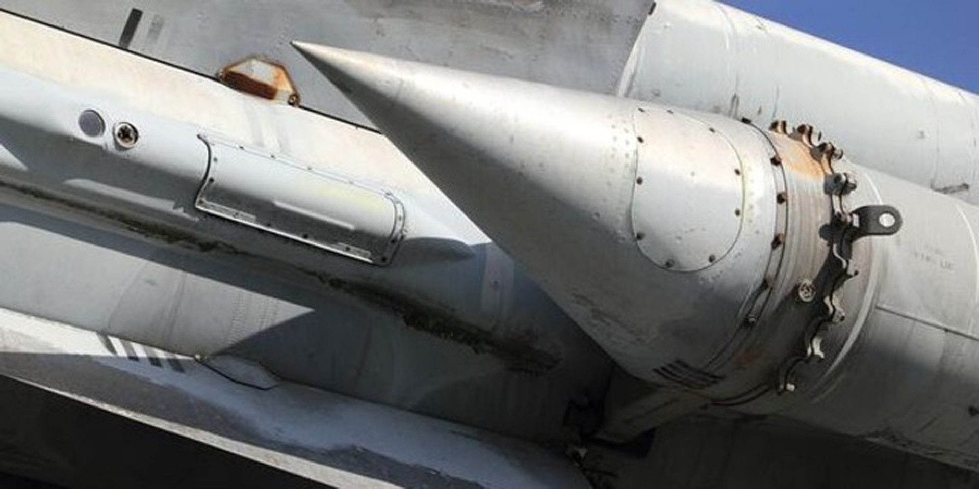 La photo illustre une partie d’un système vecteur de missiles. Elle montre un contenant métallique doté d’un capot conique.